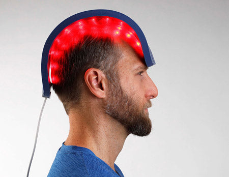 A man using a hair restoration LED light therapy device