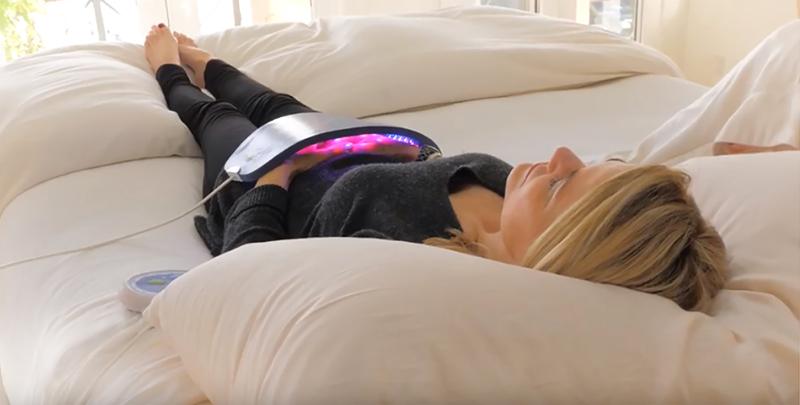 Woman using Celluma LED Therapy for stomach while laying in sofa