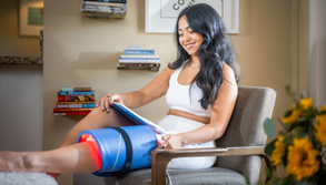 Photo of a woman sitting in a chair with her leg elevated with a Celluma red light therapy device wrapped around her knee to stimulate healing