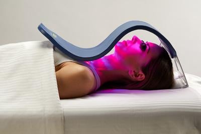 Woman lying down and using a Celluma light therapy device