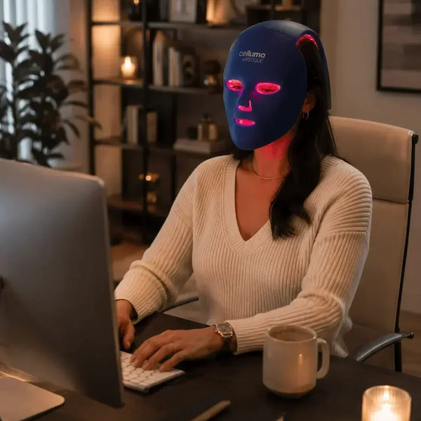 A woman wearing a Celluma MYSTIQUE LED mask while working from home.
