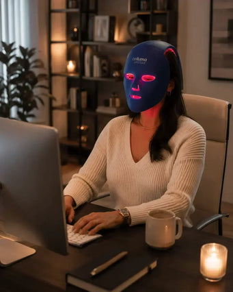 A woman wearing a Celluma MYSTIQUE LED mask while working from home.