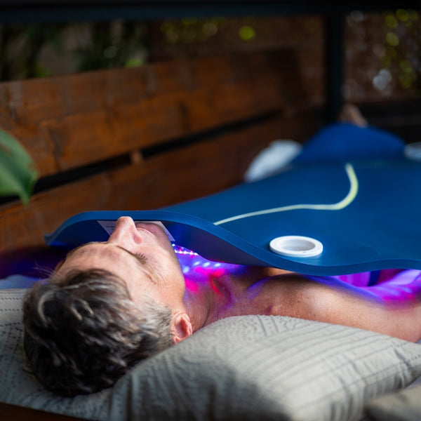 A man using a Celluma XL in his bed for a full-body LED light therapy treatment