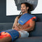 Man sitting on the couch with one device over his shoulder and another over his knees on aches and pains mode.